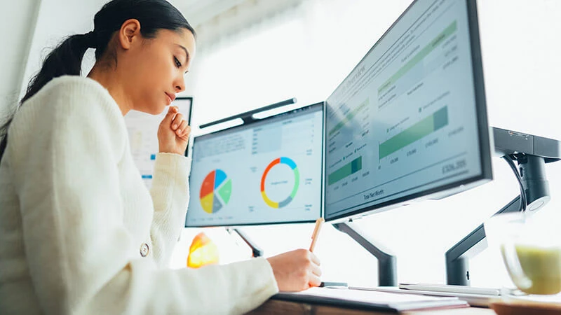 Woman sitting in front of two computer monitors with dashboards