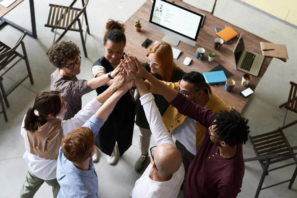 Team standing in a circle with their arms raised and hands touching