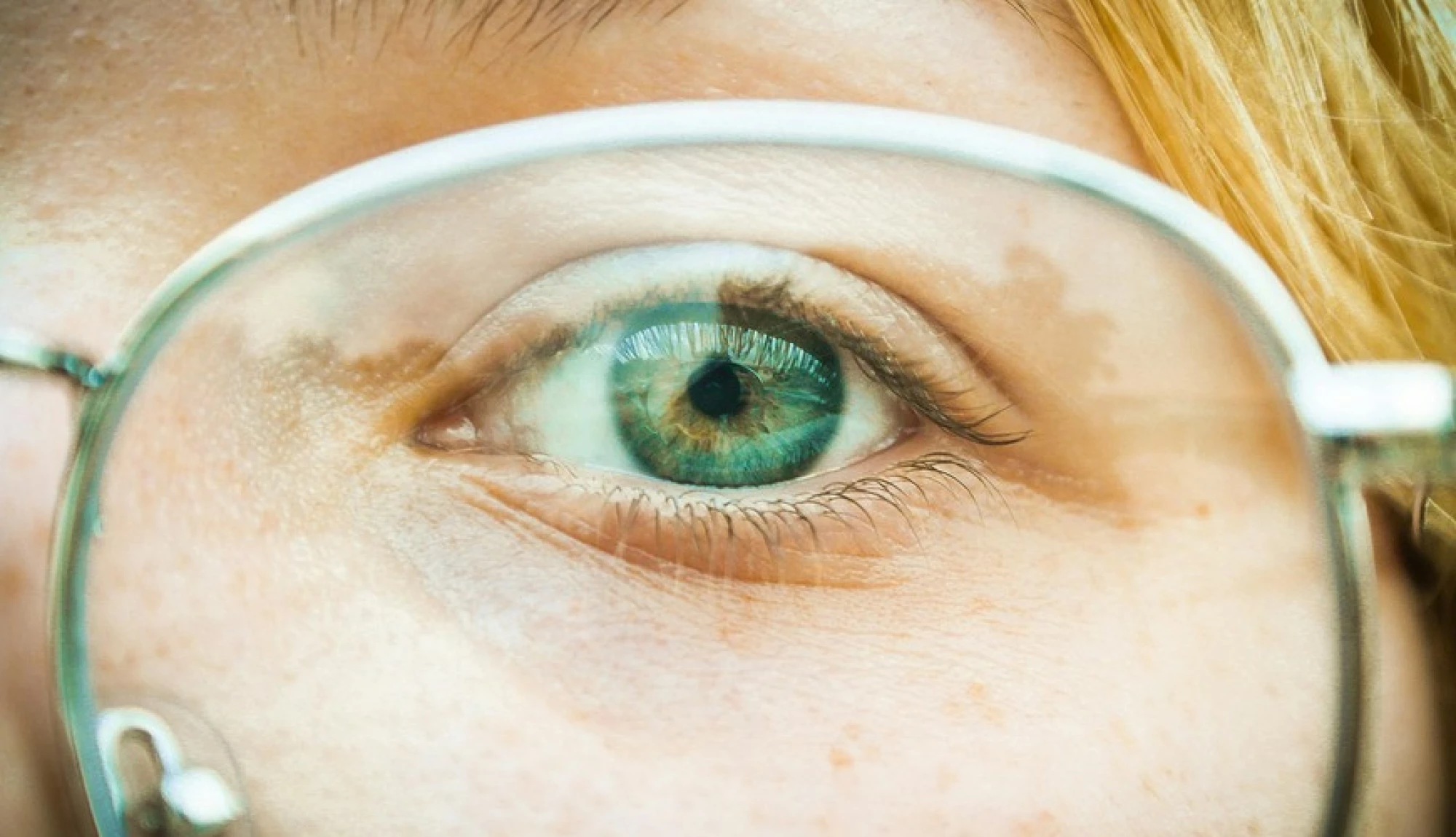 close up of a woman with her green eye and glasses