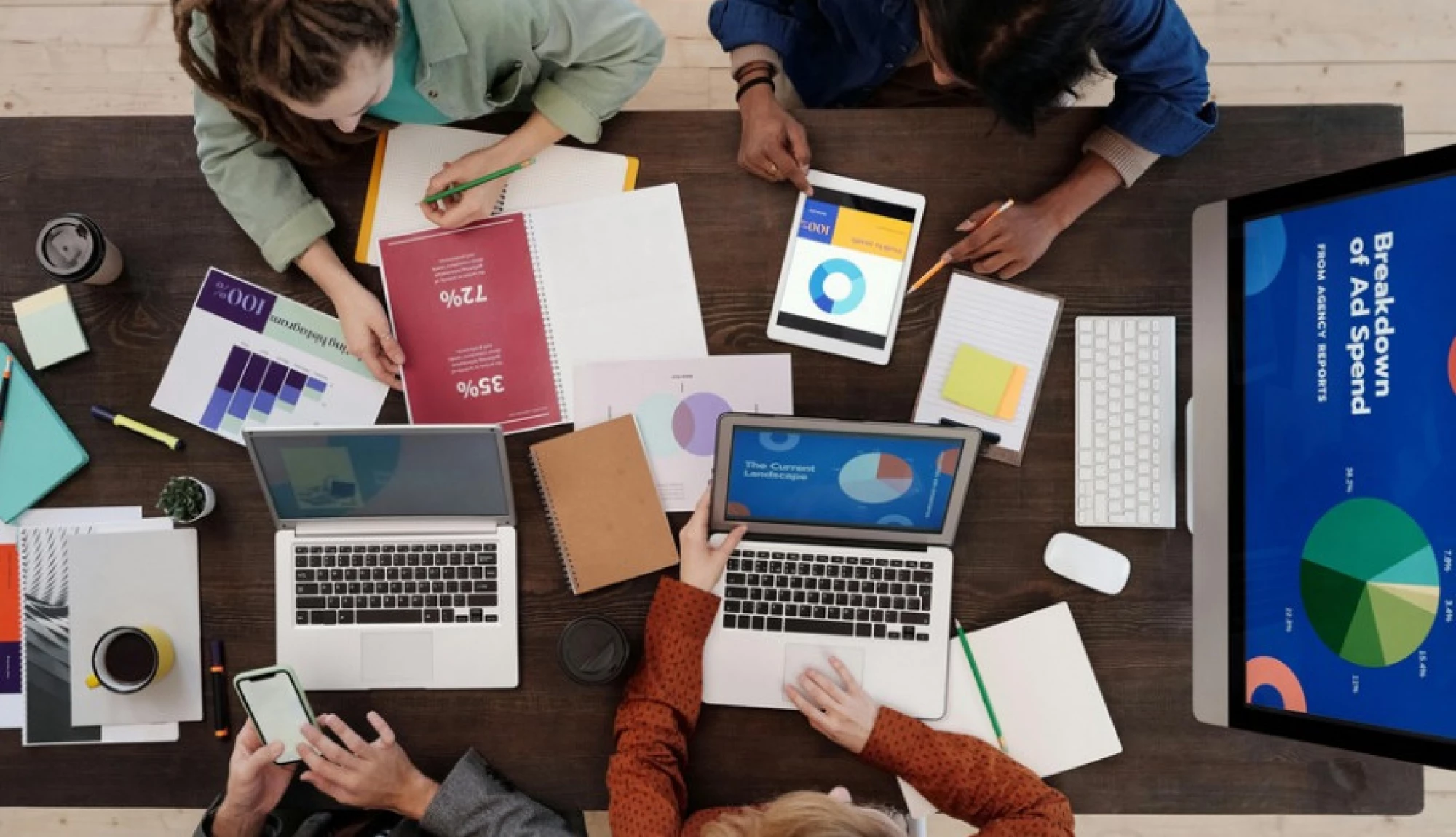 Overhead of people at a table working on their laptops