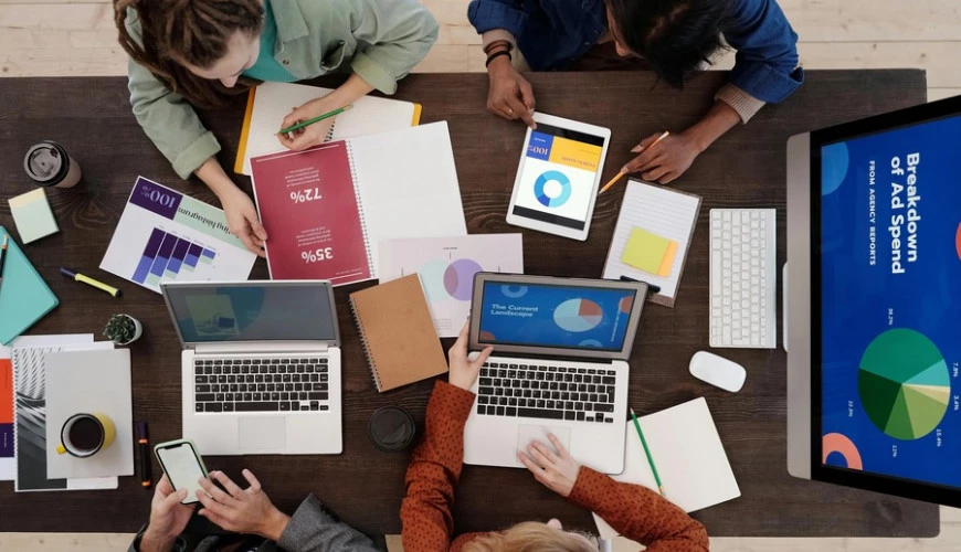 Overhead of people at a table working on their laptops