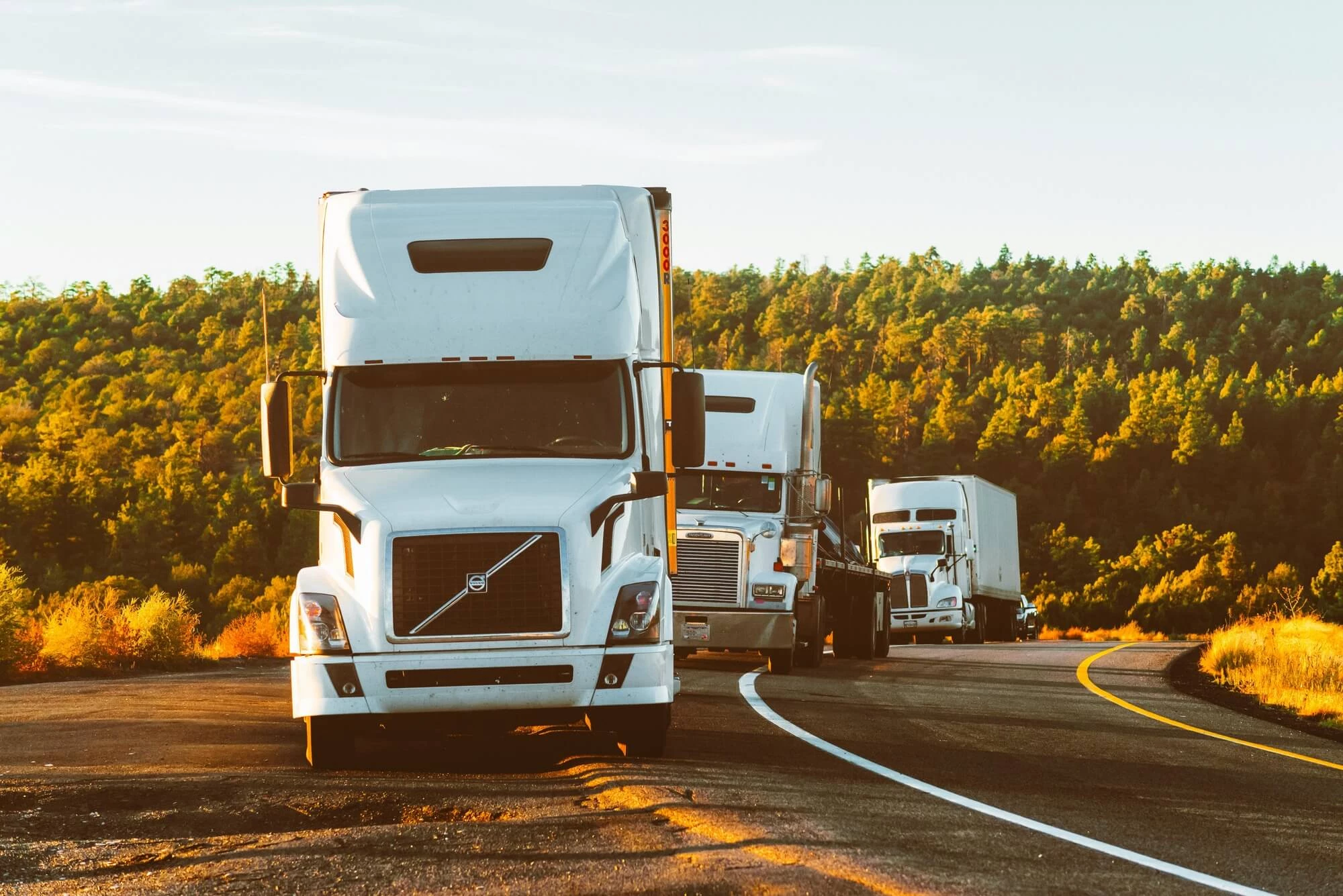 Caravan of semi trucks on the side of the road.