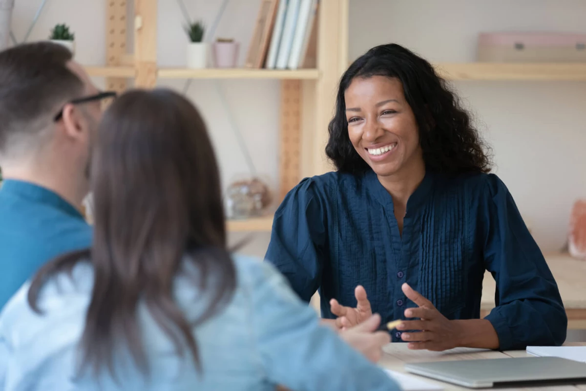 Woman at a desk speaking to a couple