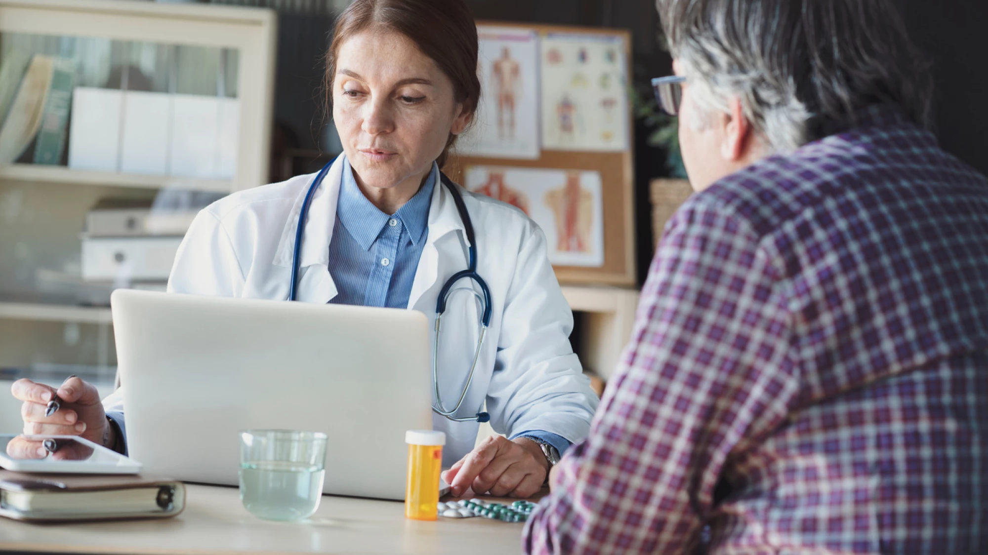 Doctor sitting across from a patient looking at her laptop