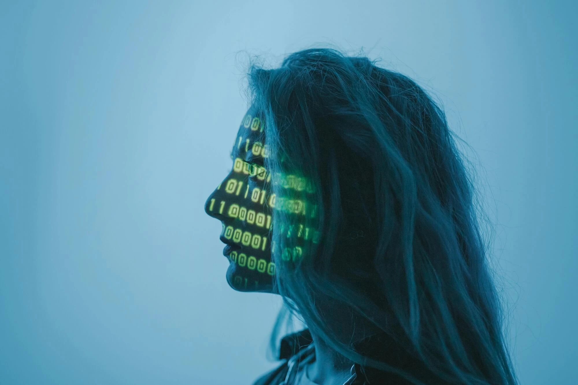 Profile view of a woman's face with green zeros and ones projected.