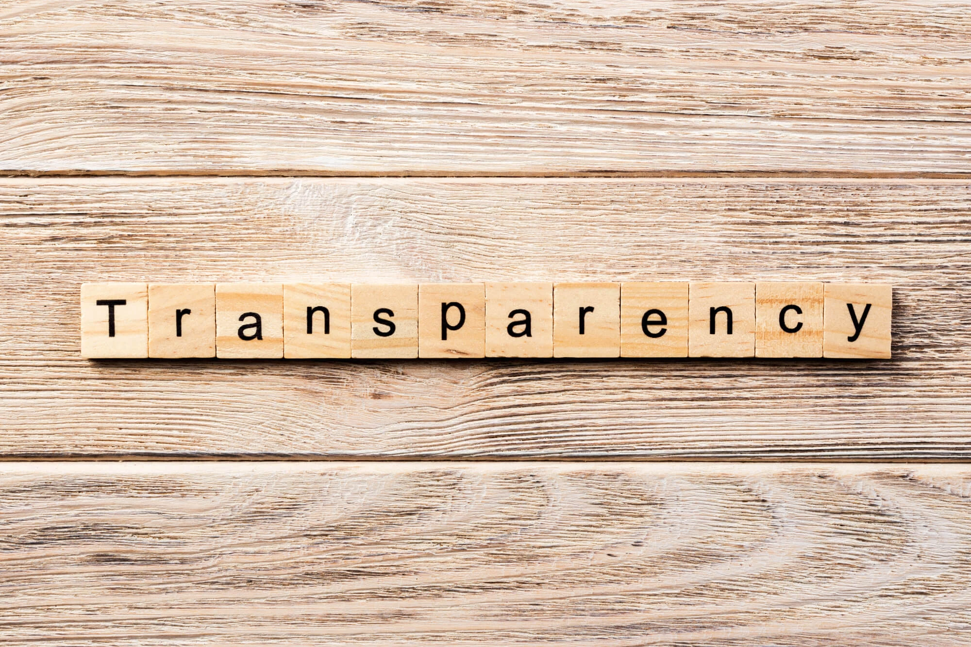 Slate wood background with Scrabble like tiles spelling out Transparency.