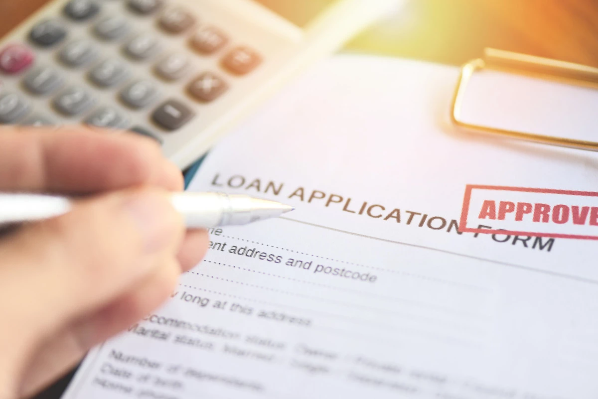 Image of loan application with person writing approved