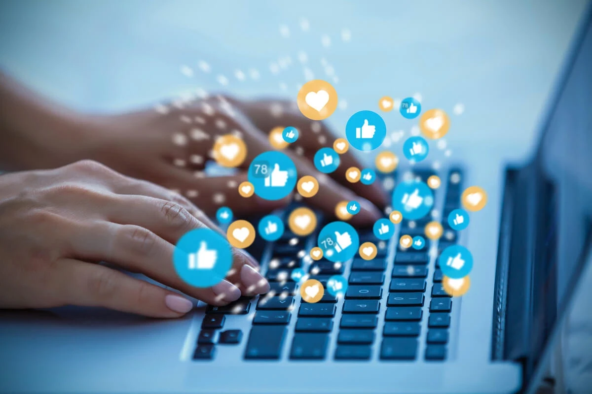 laptop with social media icons floating above it