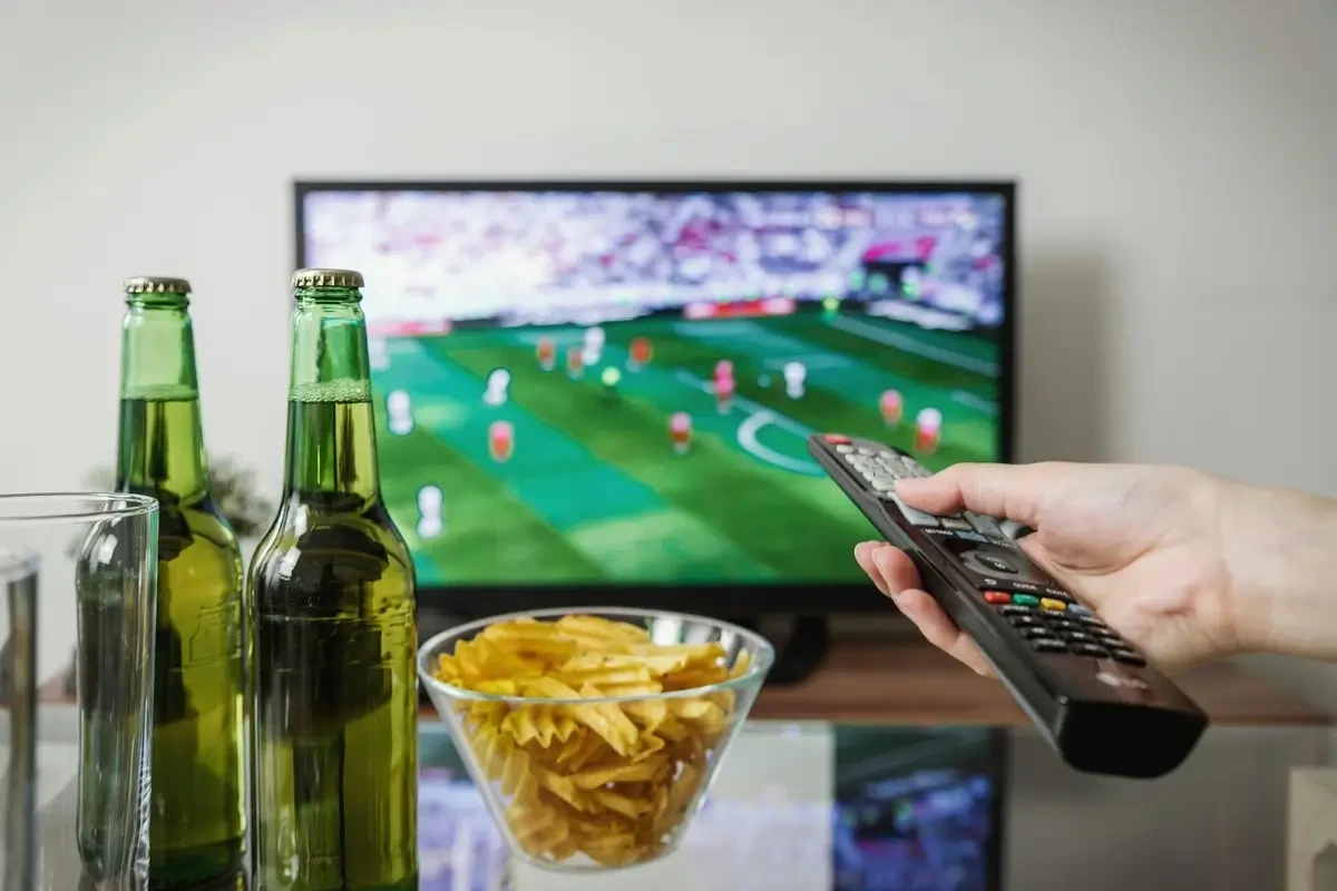hand on remote watching sports on a TV
