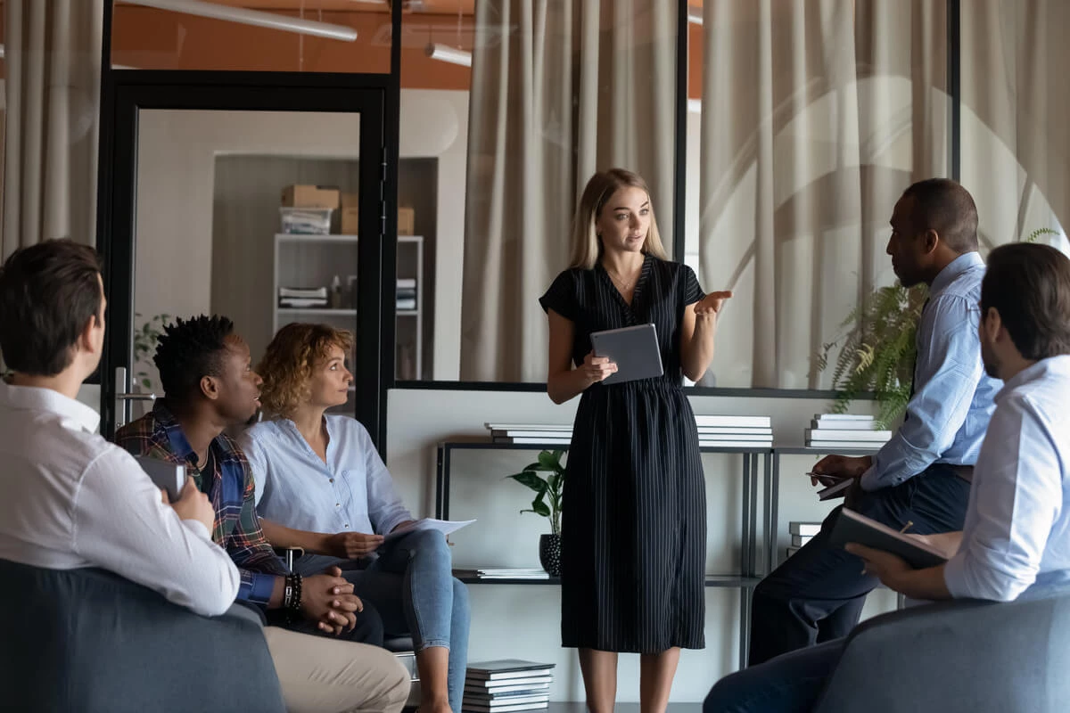 Woman presenting to a group of co workers in a conference room.